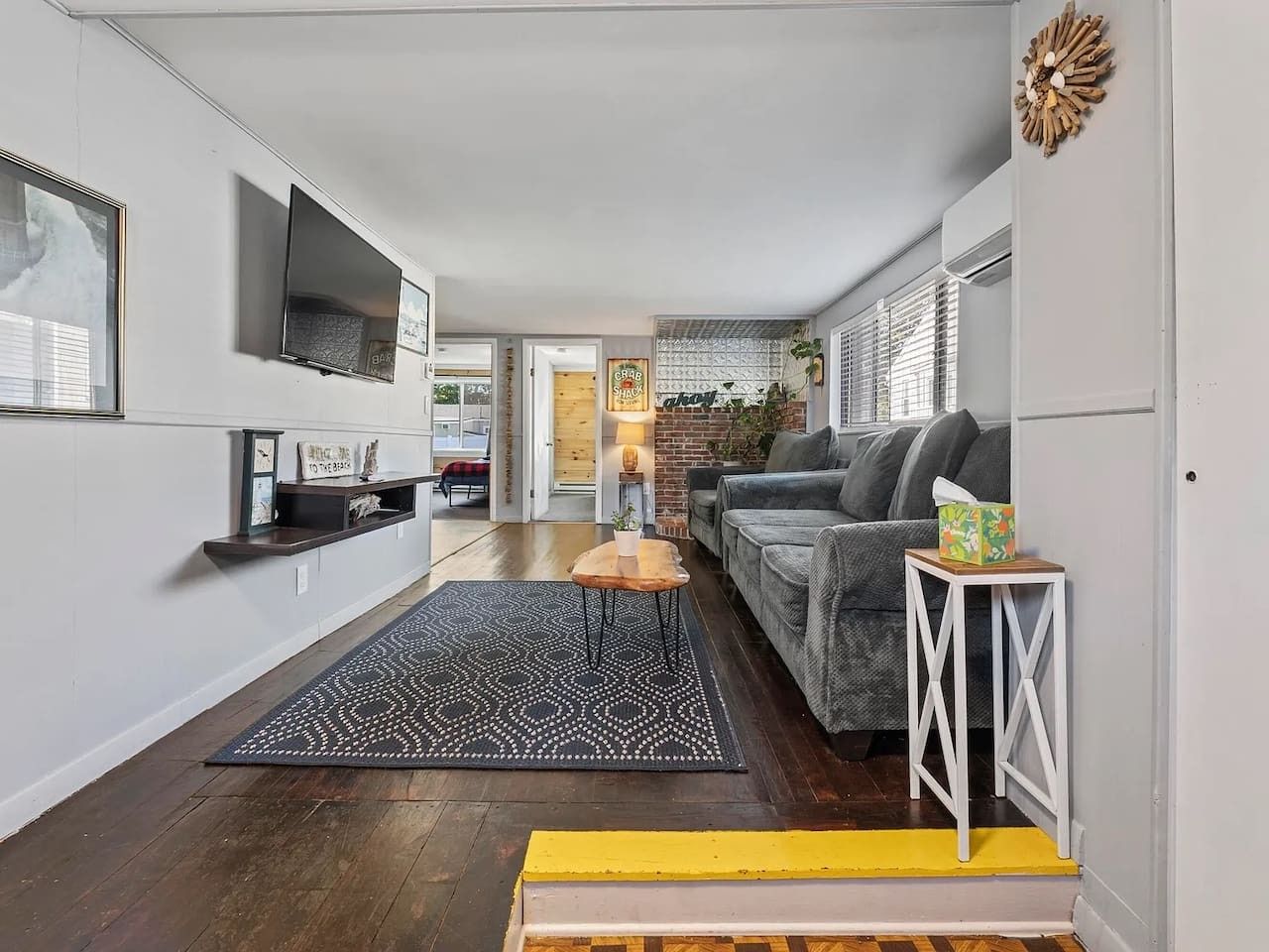 Un salon moderne avec un canapé, une table basse et un téléviseur fixé au mur.