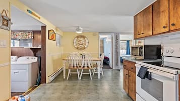 Cozinha com mesa de jantar, cadeiras, micro-ondas, forno e máquina de lavar.