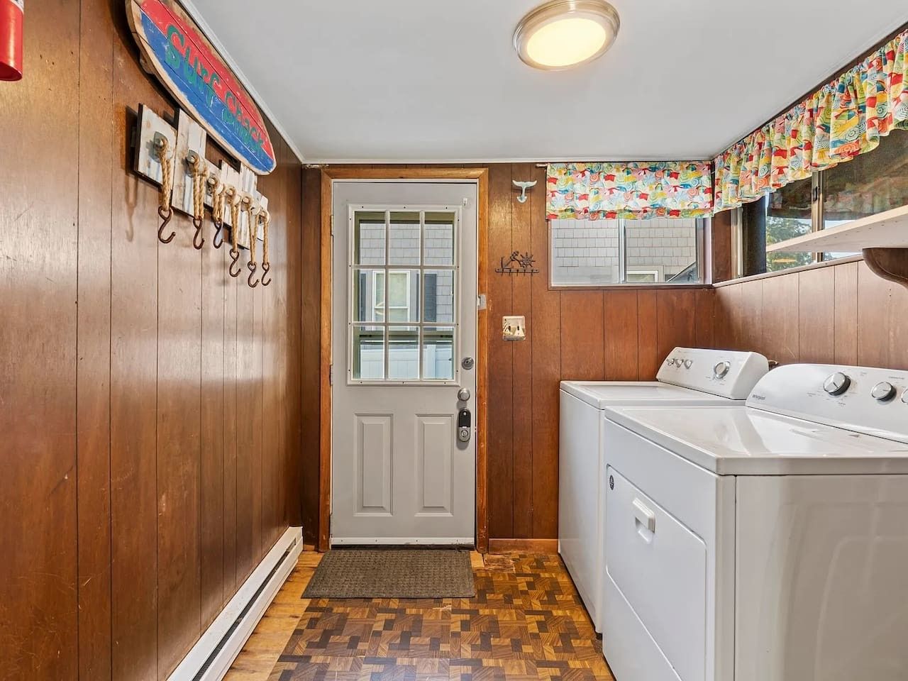 Une buanderie avec des murs en bois, une porte blanche et un lave-linge.