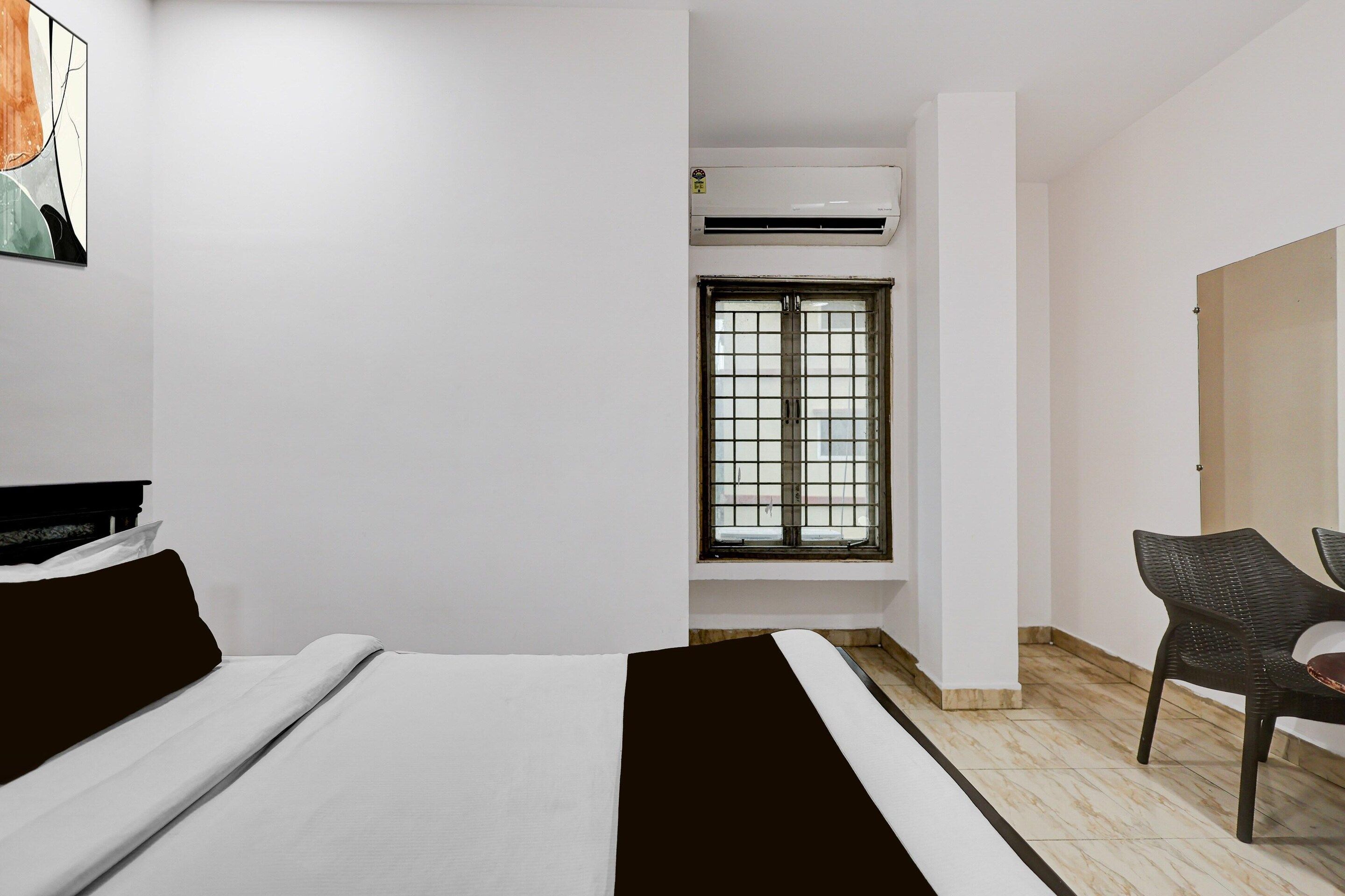 Une pièce avec un lit, une chaise, une fenêtre avec des barreaux et un appareil de climatisation.