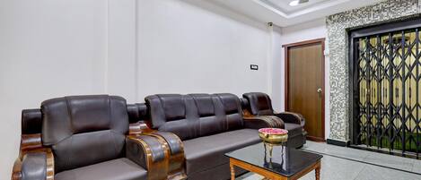 A room with a sectional sofa, a small wooden coffee table, and a ceiling fan.