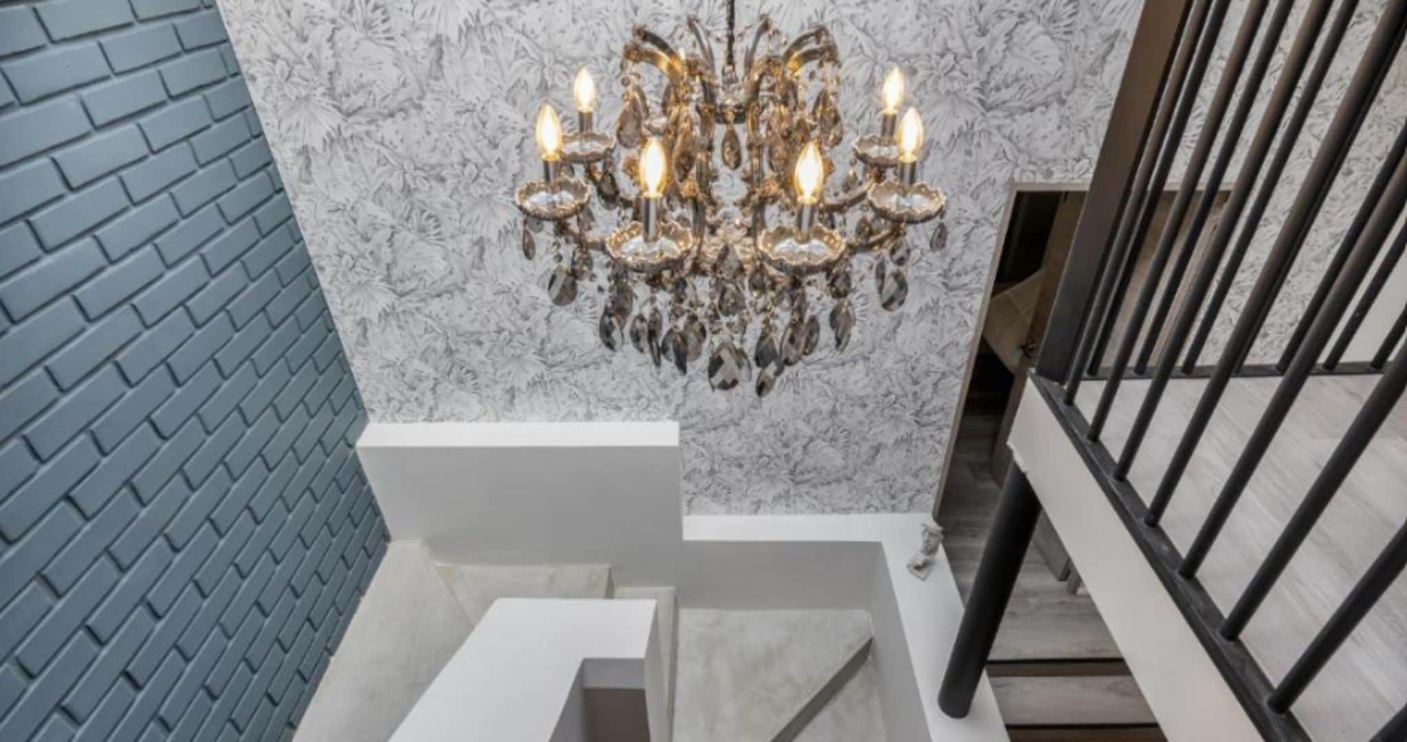 Una escalera con una pared de mármol y un candelabro.