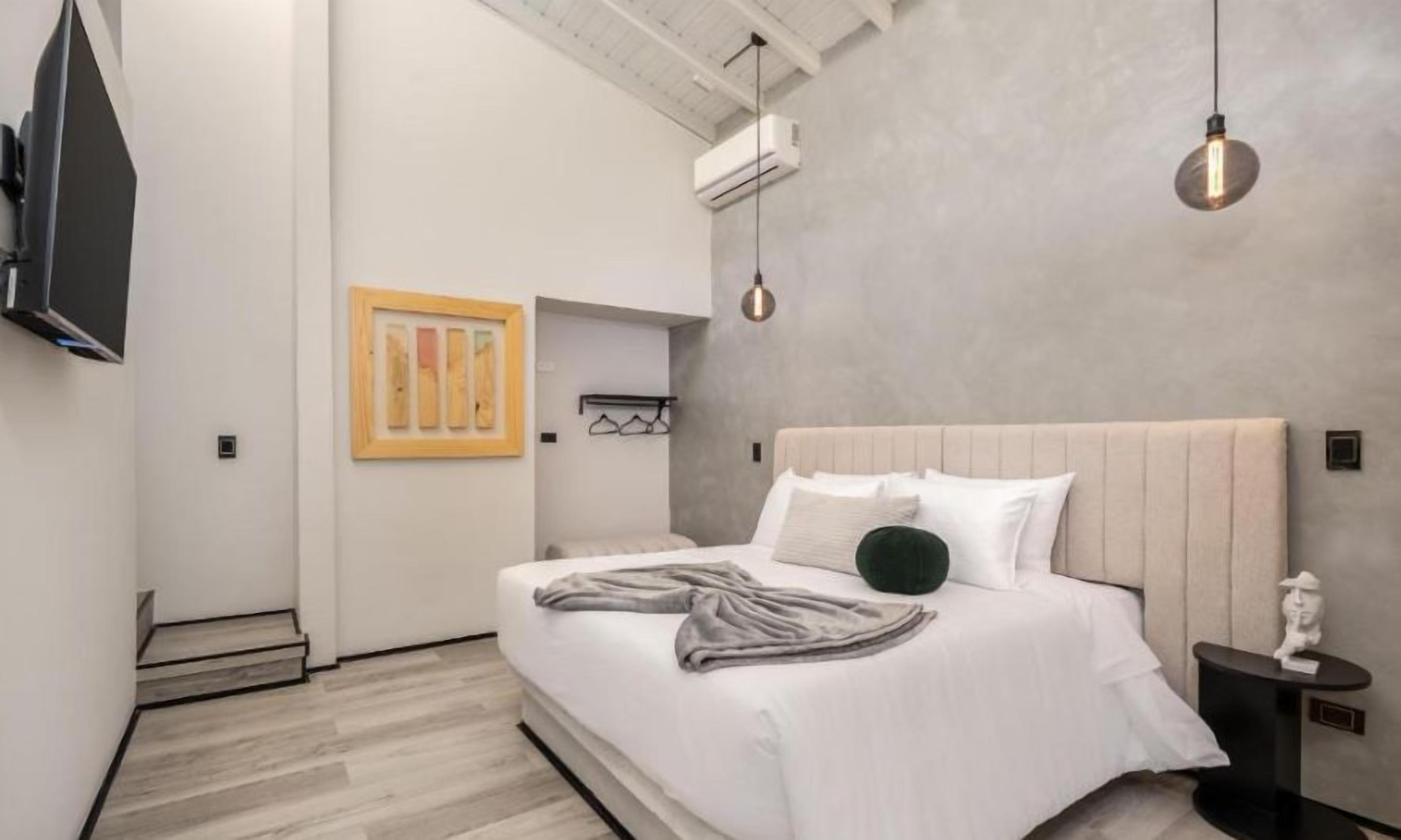 Un dormitorio moderno con una cama grande, un televisor montado en la pared y una obra de arte original.