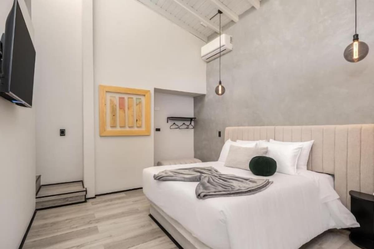 Un dormitorio moderno con una cama grande, un televisor montado en la pared y una obra de arte original.