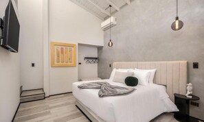 Un dormitorio moderno con una cama grande, un televisor montado en la pared y una obra de arte original.