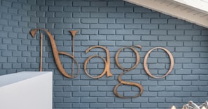 A wall with a metal sign spelling 'Nago' against a brick wall. - NAGO HOMETEL (Medellín)