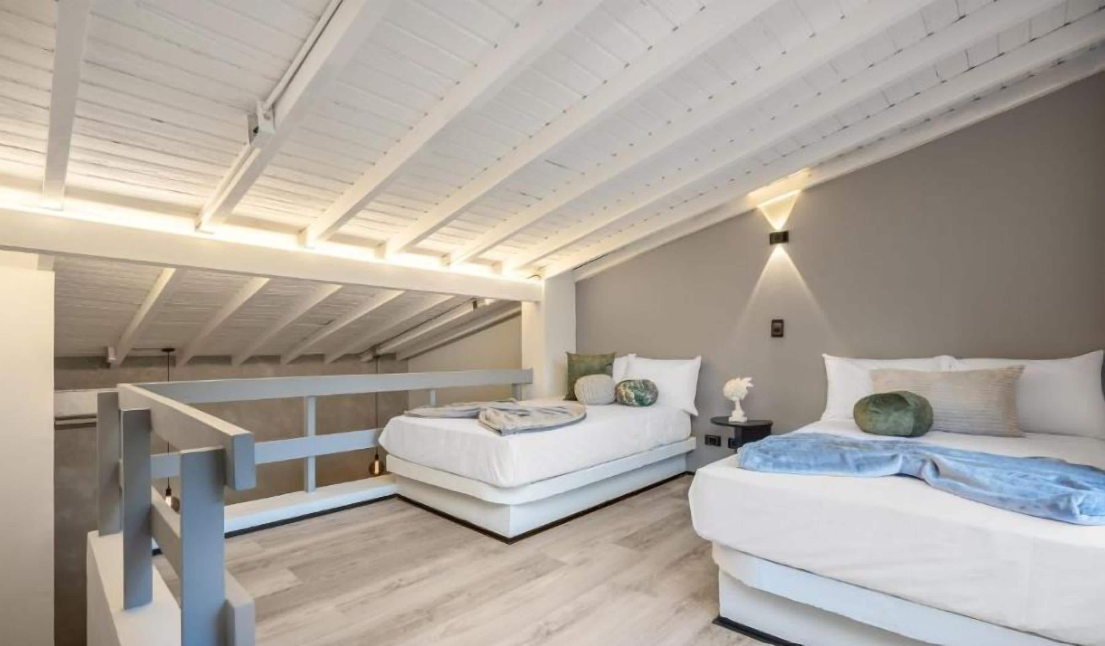Ein Schlafzimmer mit zwei Betten, einer Holzbalkendecke und einem Nachttisch mit Lampe.