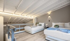 A bedroom with two beds, a wooden ceiling, and a nightstand with a lamp. - NAGO HOMETEL (Medellín)