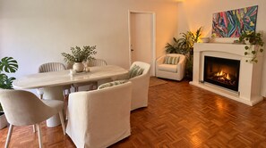A living room with a fireplace, a dining table with chairs, and a sofa.