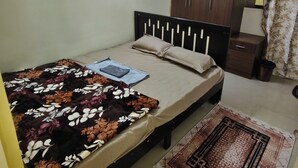 Een slaapkamer met een bed, een nachtkastje, een garderobe, een spiegel en een kamerkleed met dessin.