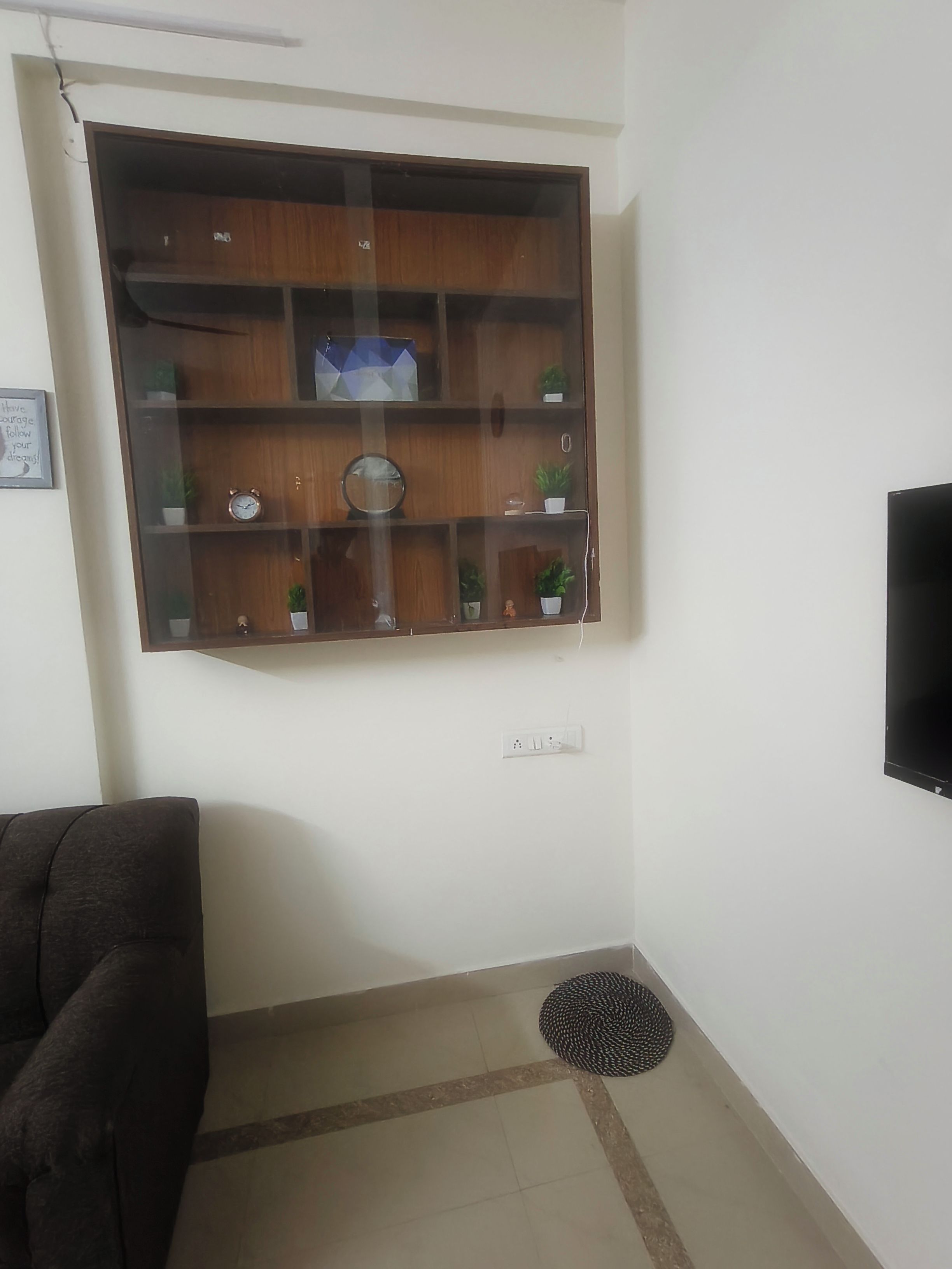 Una sala de estar con un aparador de madera, un televisor, un sofá y una alfombra pequeña.