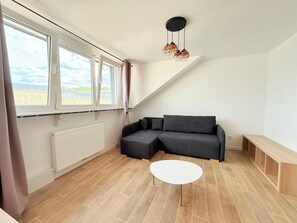 Una sala de estar moderna con un sofá modular, una mesa de centro blanca y vistas al exterior a través de amplios ventanales.