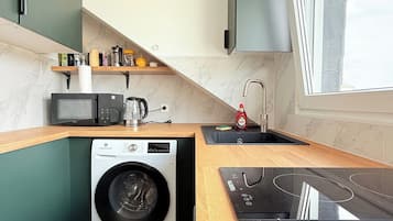 Cozinha compacta com máquina de lavar, micro-ondas e fogão embutido.