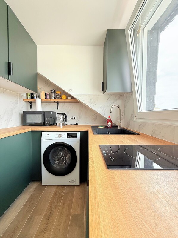 A compact kitchen with a washing machine, microwave, and a built-in stove.