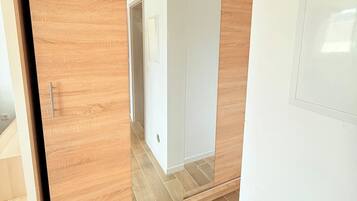 Quarto com guarda-roupa de madeira deslizante e porta branca.