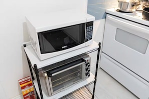 Une cuisine équipée d’un four à micro-ondes et d’un four grille-pain sur un chariot, à côté d’une cuisinière.