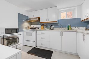 A modern kitchen with white cabinets, a built-in oven, a microwave, and a toaster.