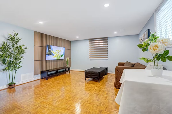 Un salon moderne avec un téléviseur à écran plat, un canapé, une table basse et une plante en pot.