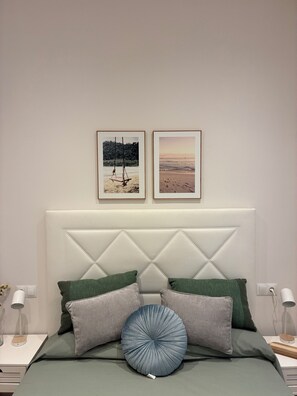 A bedroom with a bed, pillows, a headboard, and two framed pictures on the wall.
