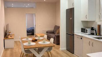 Een knus woongedeelte met een eethoek, kitchenette en een bank.