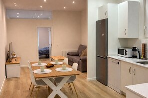 A compact living space with a dining area, kitchenette, and a sofa.