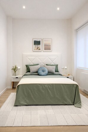 A bedroom with a bed, bedside tables, a nightstand, a window, and two wall-mounted pictures.