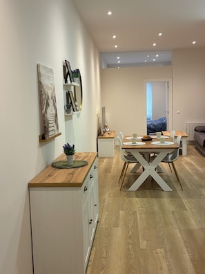 A modern kitchen with a dining area, wooden cabinets, and a view into the living room.