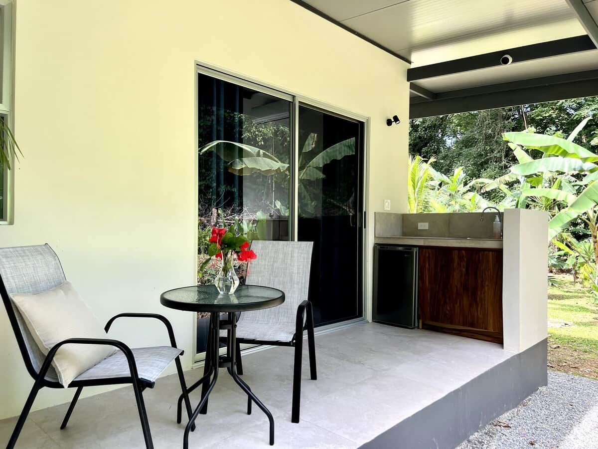 A patio with two chairs and a table, a sliding glass door, and a small kitchen area.