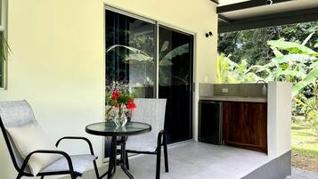 A patio with two chairs and a table, a sliding glass door, and a small kitchen area.