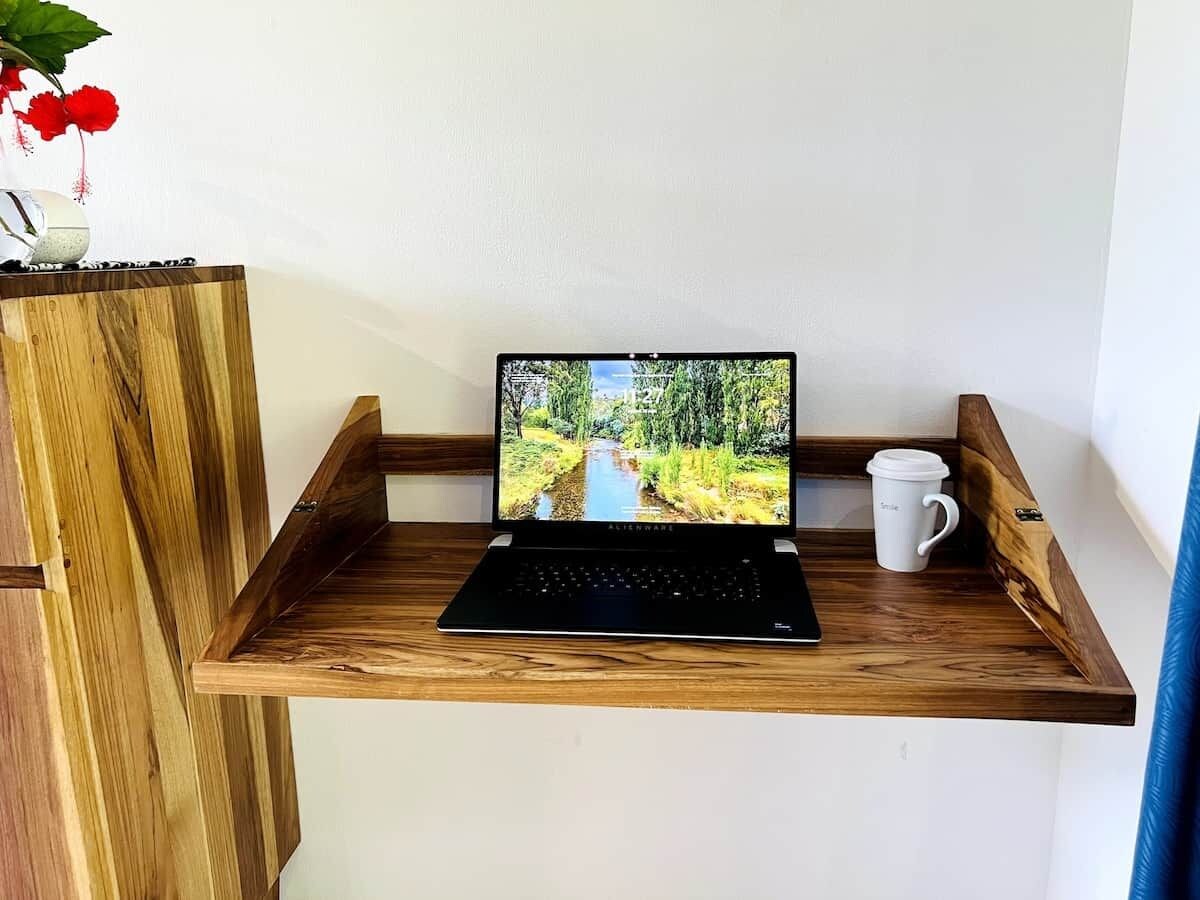 Een laptop op een houten plank, met een witte mok ernaast.