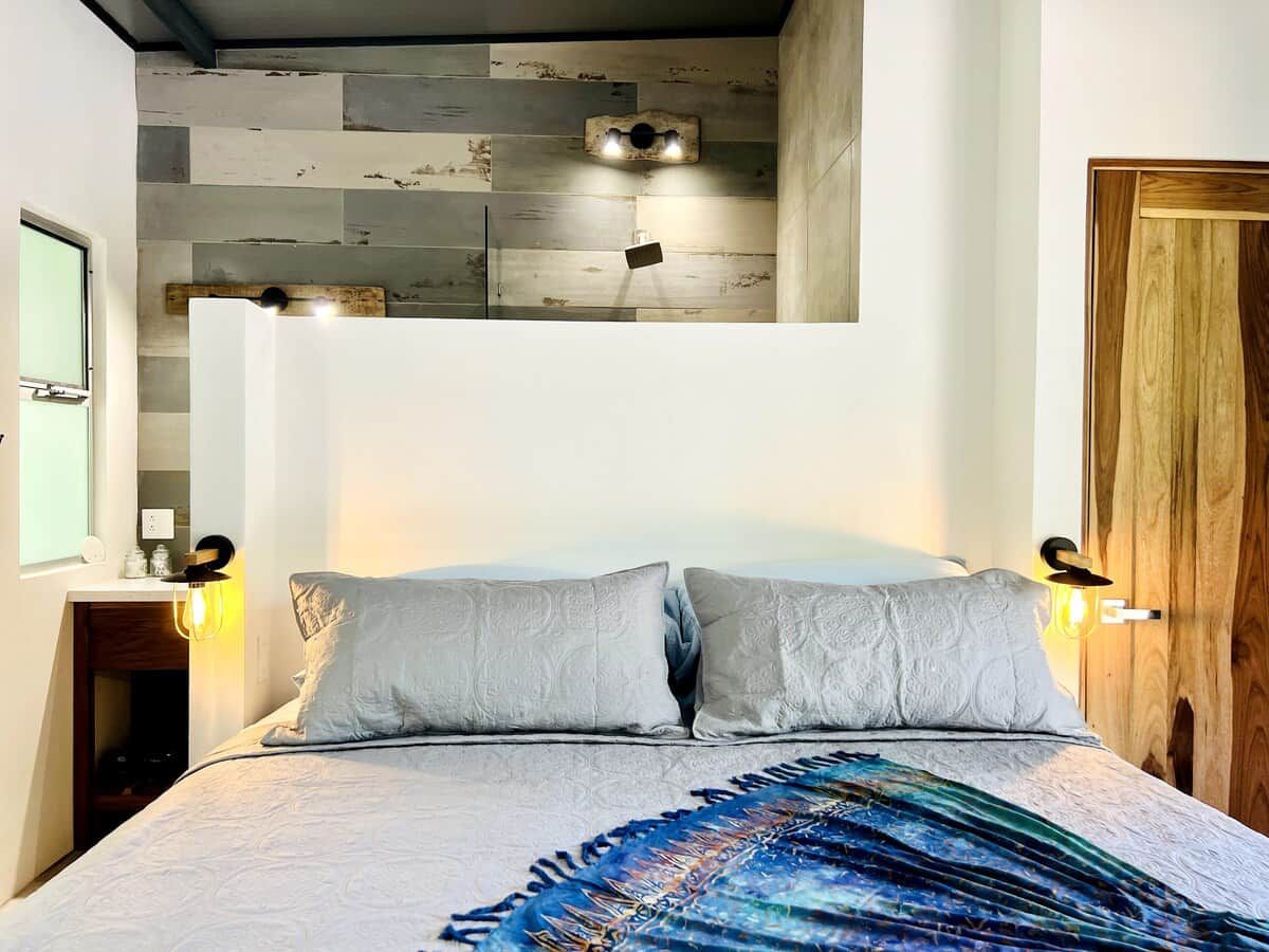 Ein Schlafzimmer mit einem Bett, zwei Wandleuchten und einer Holztür.