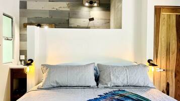 Ein Schlafzimmer mit einem Bett, zwei Wandleuchten und einer Holztür.