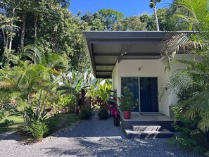 Una casa moderna con porche cubierto, rodeada de exuberante vegetación tropical.