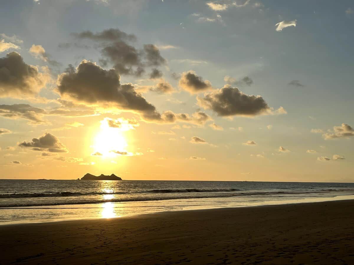 Een strand met een zonsondergang en wolken.