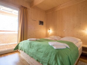 A room with a bed, a window with curtains, and a wall-mounted light. - Cabin in Turrach With Sauna and Balcony (Stadl-Predlitz)