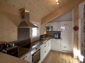 A modern kitchen with wooden cabinetry, a built-in microwave, and a stove. - Cabin in Turrach With Sauna and Balcony (Stadl-Predlitz)