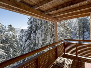 A wooden balcony with a metal railing overlooking a snowy forest. - Cabin in Turrach With Sauna and Balcony (Stadl-Predlitz)