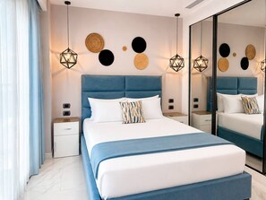 A modern bedroom with a large bed, bedside tables, a mirror, and wall decor. - Cana Bay | Near Hard Rock & Beach Club (Punta Cana)