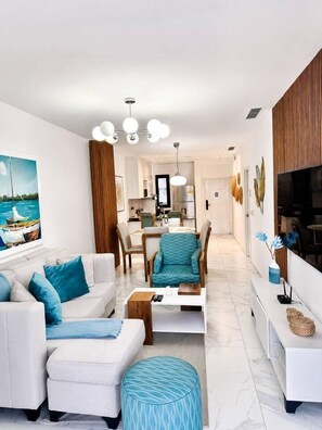 A modern living room with a sofa set, a coffee table, and a television. - Cana Bay | Near Hard Rock & Beach Club (Punta Cana)