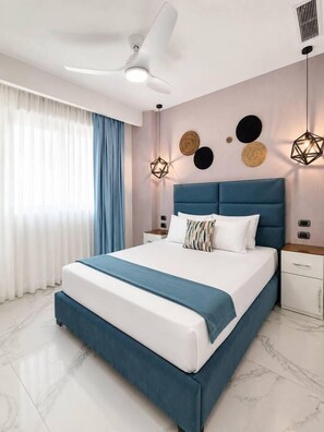 A modern bedroom with a large bed, a ceiling fan, and decorative wall art. - Cana Bay | Near Hard Rock & Beach Club (Punta Cana)