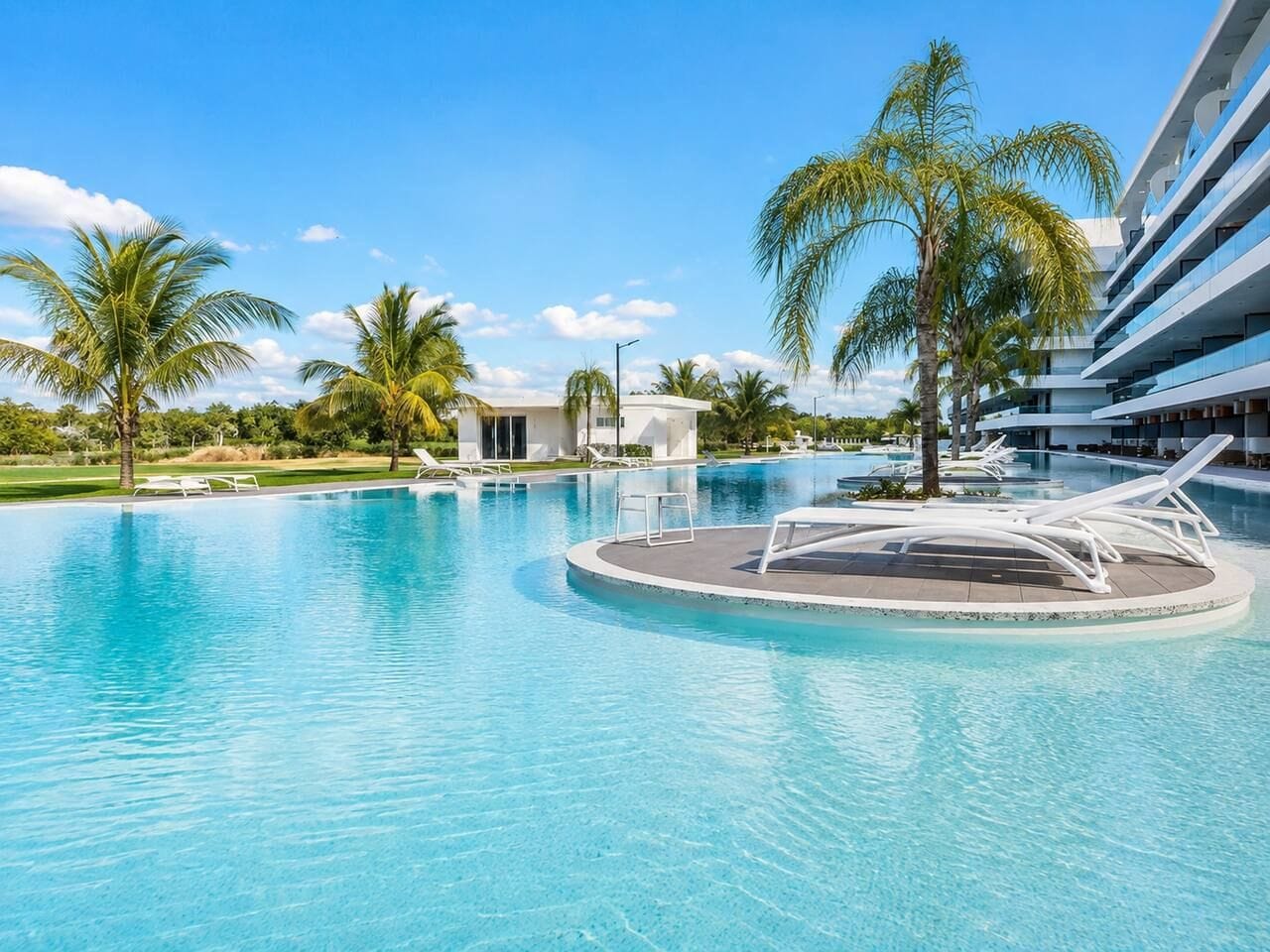 A swimming pool with lounge chairs and palm trees.