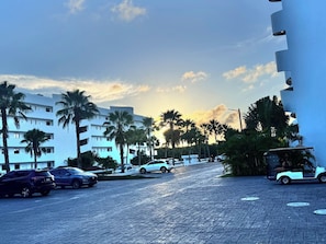 A paved street with parked cars, palm trees, and a building with balconies. - Cana Bay | Near Hard Rock & Beach Club (Punta Cana)