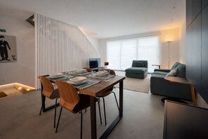 Ein modernes Wohnzimmer mit Essbereich, einer Couch und einem Fernseher.