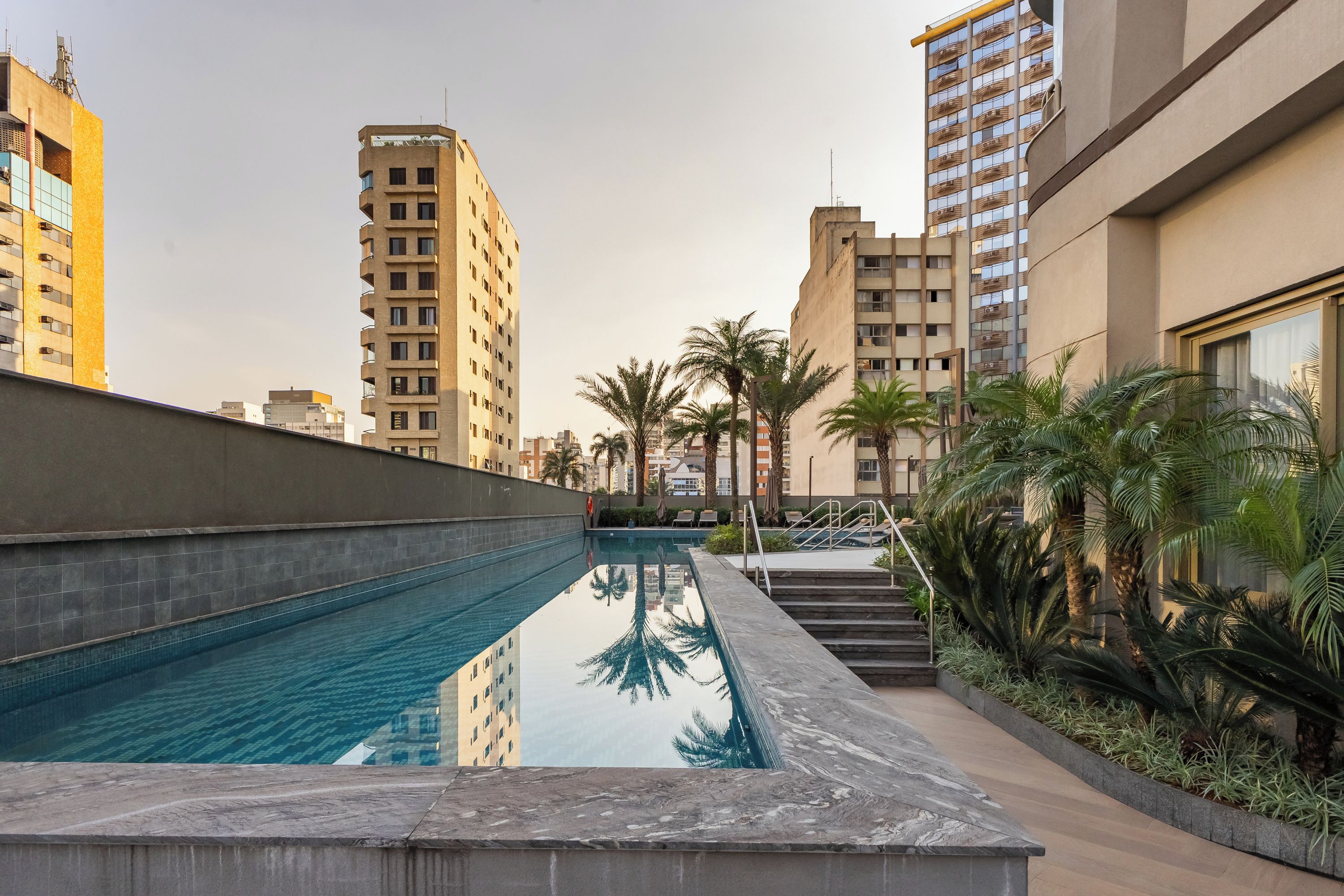 A swimming pool with a clear view of the surrounding buildings and palm trees.