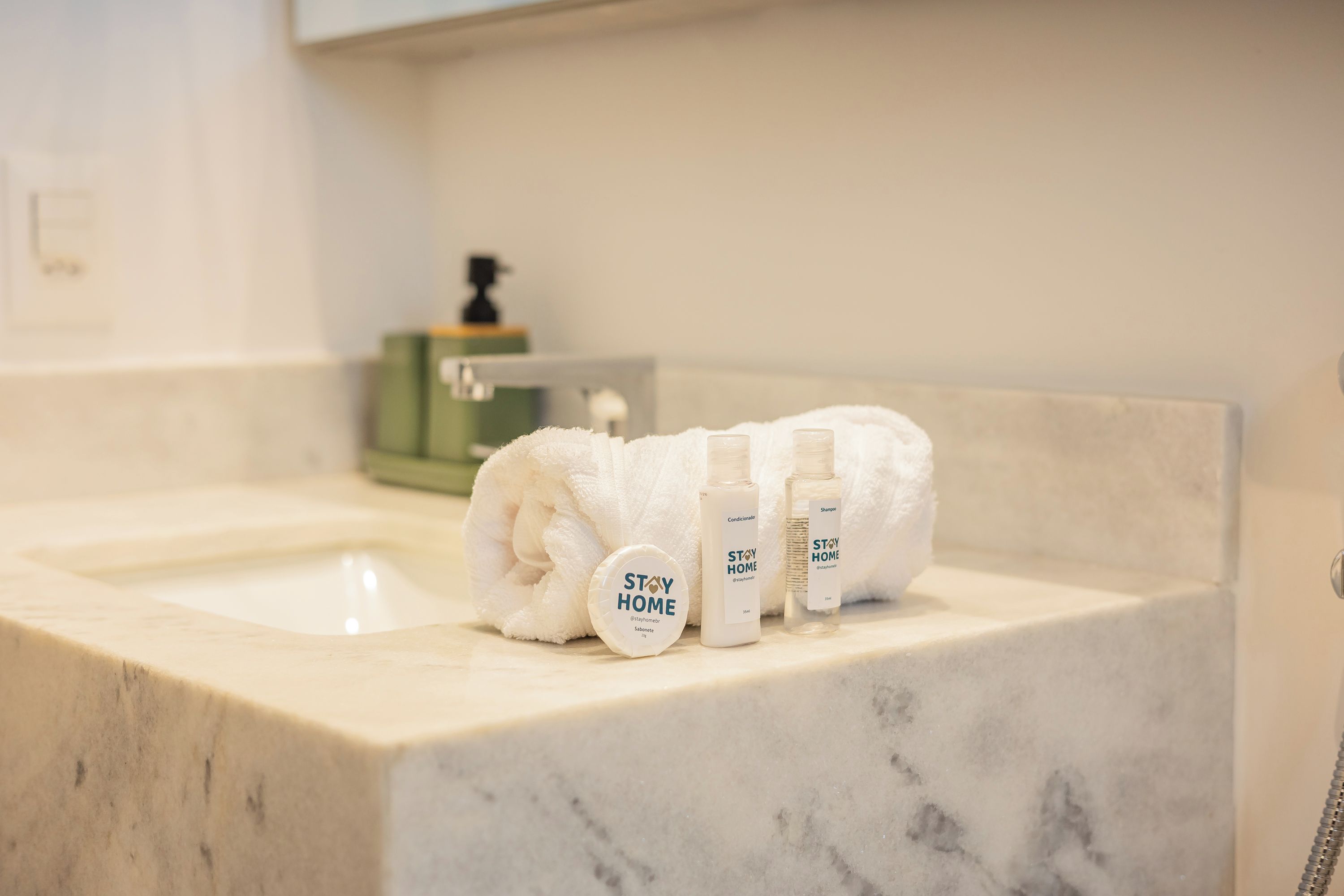 Ett badrum med ett handfat i marmor, en handduk och hygienartiklar.