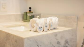 Ett badrum med ett handfat i marmor, en handduk och hygienartiklar.