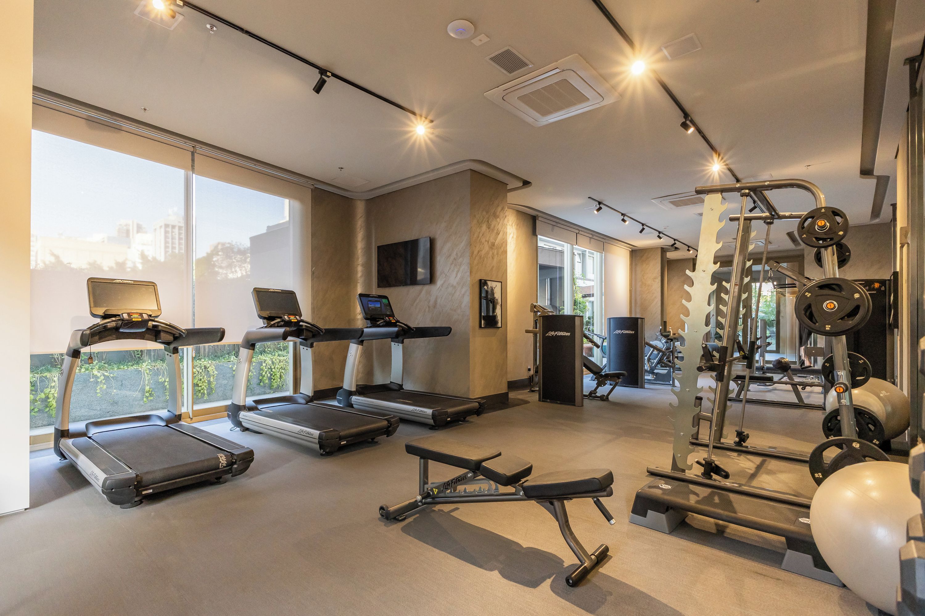 A gym with treadmills, a weight bench, and exercise equipment.