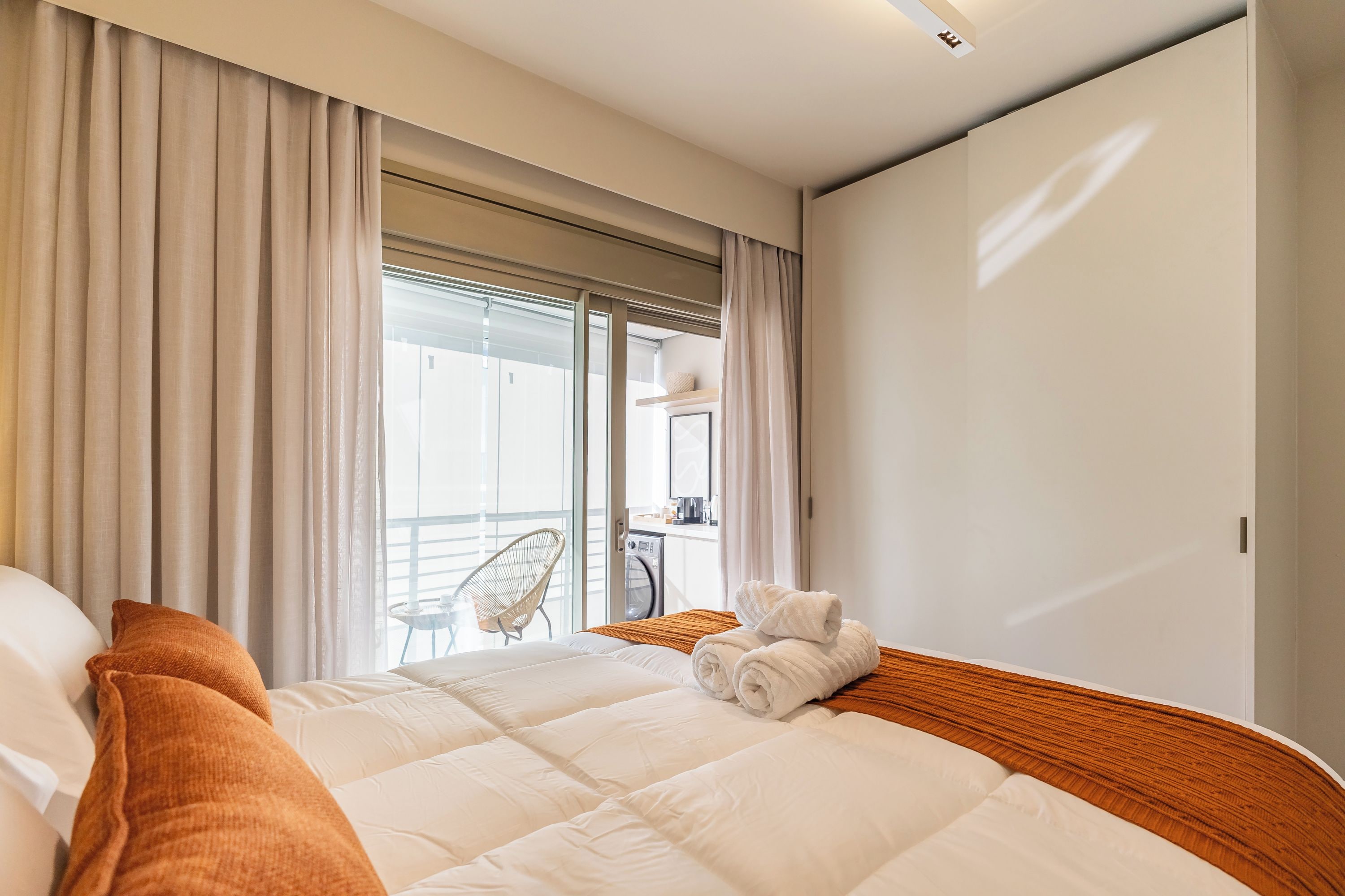 Habitación de hotel con una cama grande, una silla y vistas al exterior.