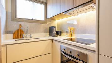 Una cocina moderna con horno empotrado, cafetera y utensilios de madera sobre la encimera.