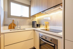 Una cocina moderna con horno empotrado, cafetera y utensilios de madera sobre la encimera.